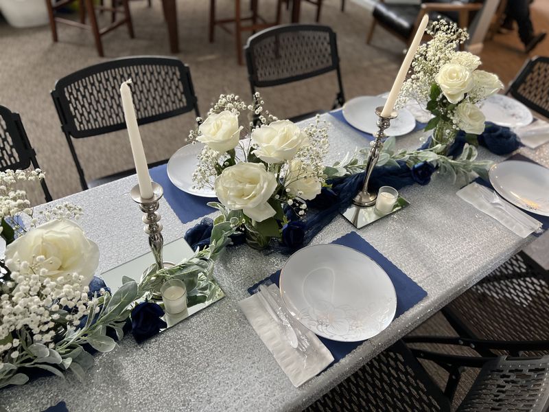 Elegant tablescape with white roses, baby's breath, navy linens and silver runner
