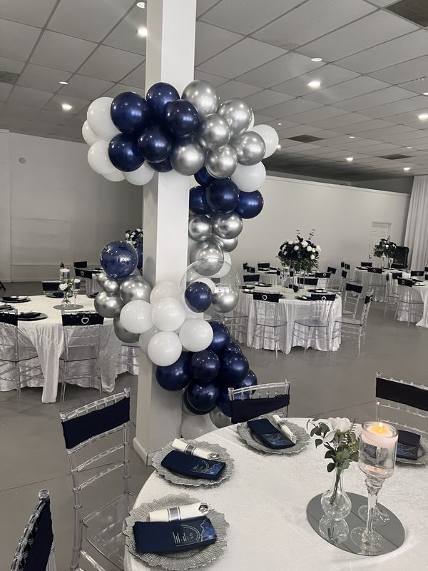 Navy, silver and white balloon installation in a banquet hall with set tables